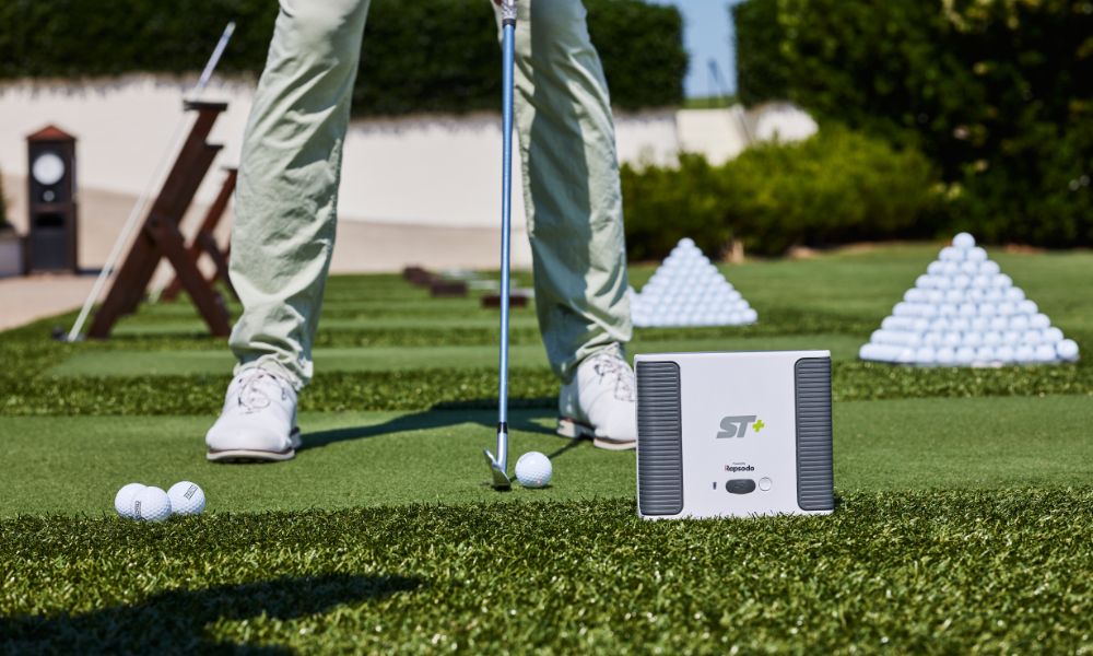 Person practicing golf swings on a driving range with a portable launch monitor.